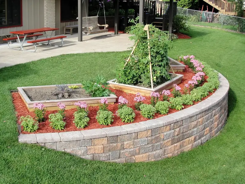 Curved segmental block retaining wall holding a raised planting bed