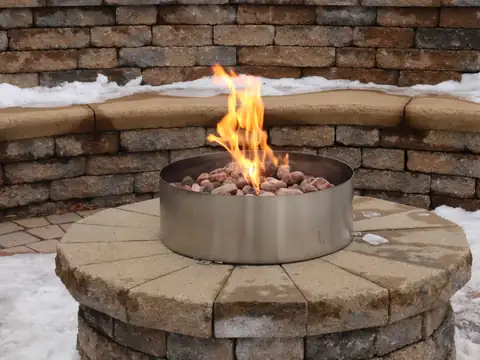 Fire burning in a round fire pit ringed by a seating wall