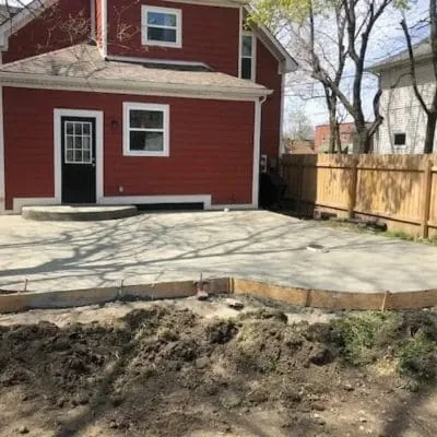 Fresh concrete back patio poured beside a red house