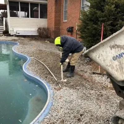 Crew member working the stone base around a kidney-shaped pool