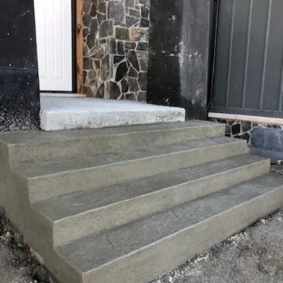 New poured concrete front steps at a house with a stone front