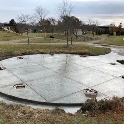 Round concrete patio slab with scored joints in a large backyard